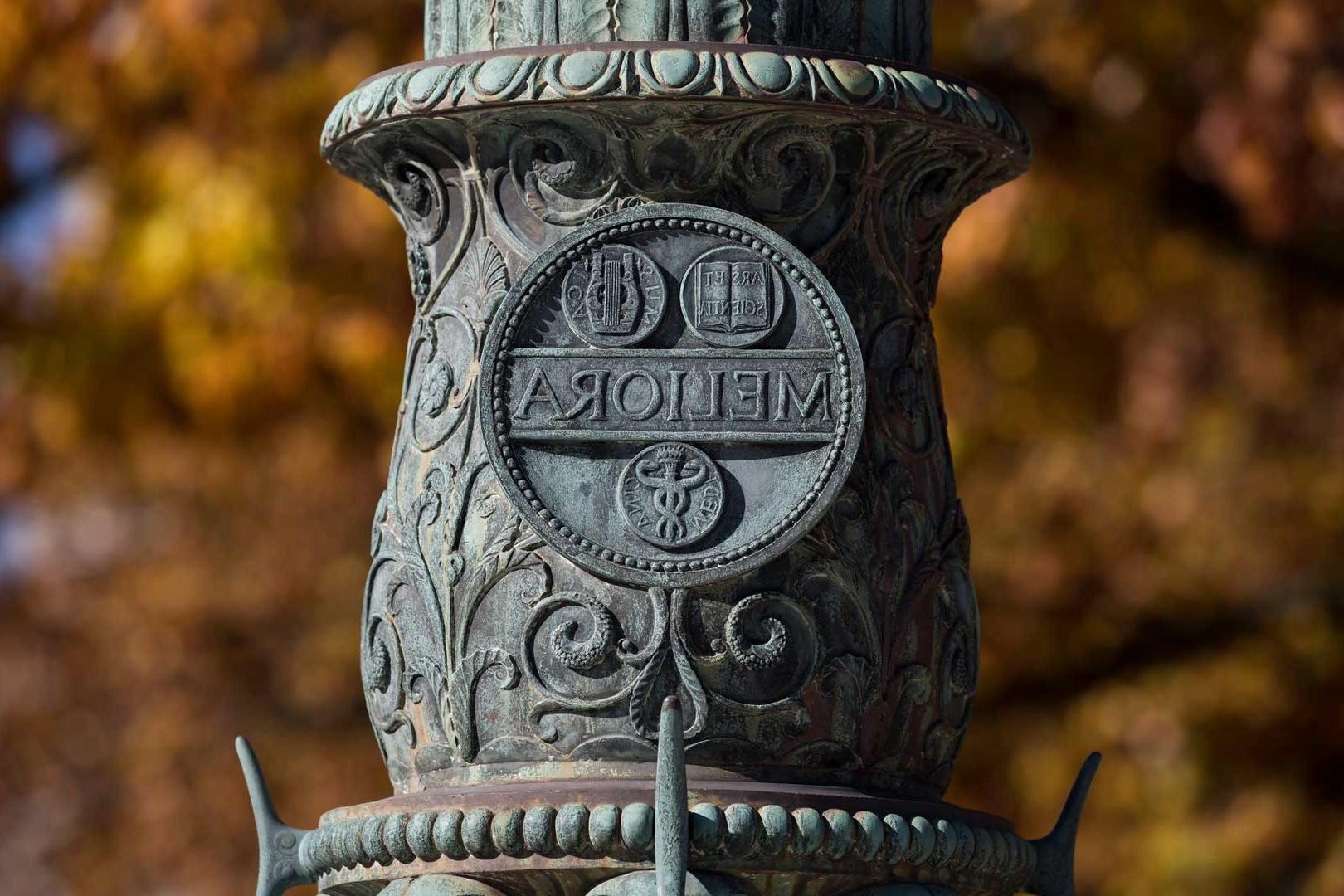 关闭-up of the Meliora seal inscription on flagpole on Eastman Quad at the University of Rochester